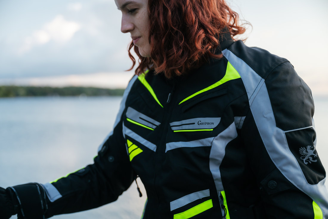 woman with red hair at the beach wearing a gryphon motorcycle jacket looking down