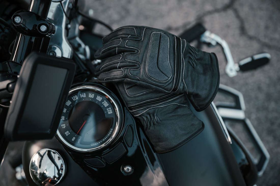 gryphon motorcycle gloves laying on the tank of a motorcycle looking down at the gloves and speedometer