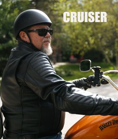 a man on a harley davidson motorcycle wearing a gryphon leather jacket and helmet and sunglasses 