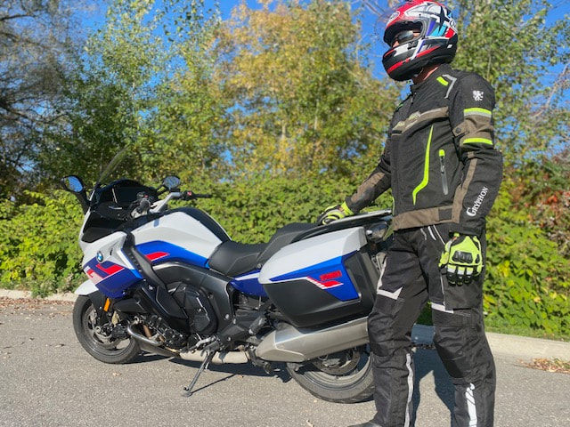 man standing beside a bmw motorcycle wearing a helmet and wearing Gryphon motorcycle jacket, pants and gloves