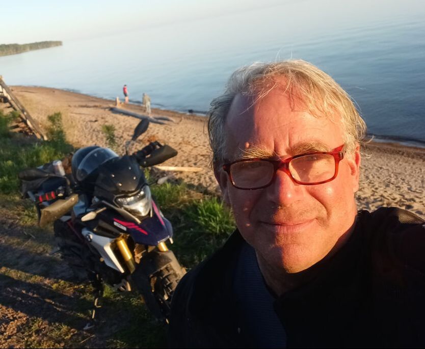 man at the beach with his motorcycle behind him 