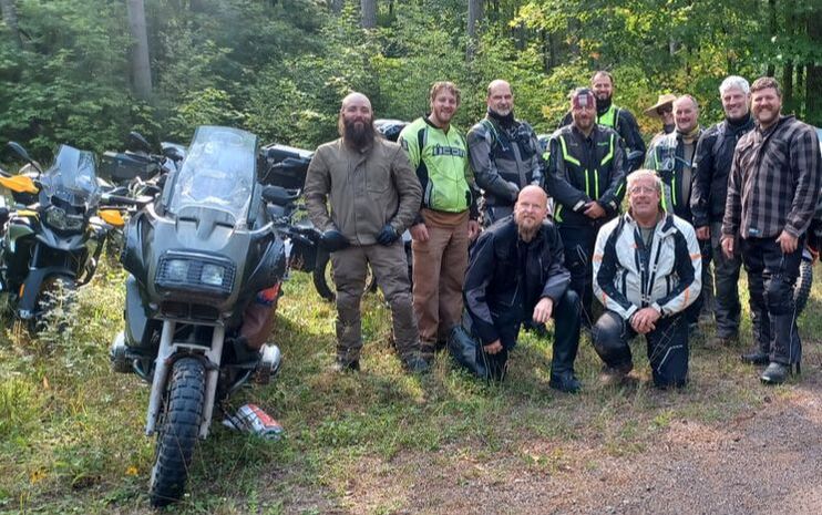 a group of men with their motorcycles on a ride through the forest
